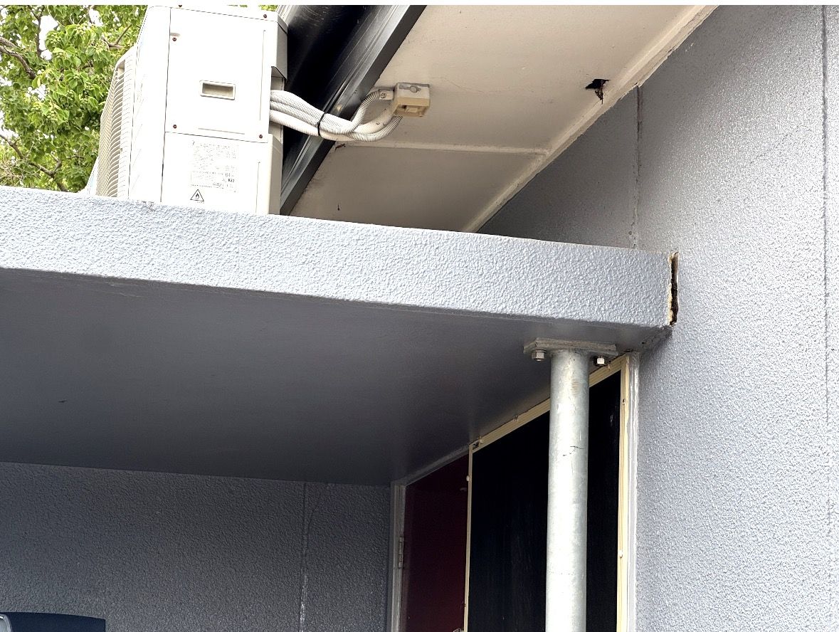 Underside of a concrete awning and its junction with a rendered wall, supported by a steel post