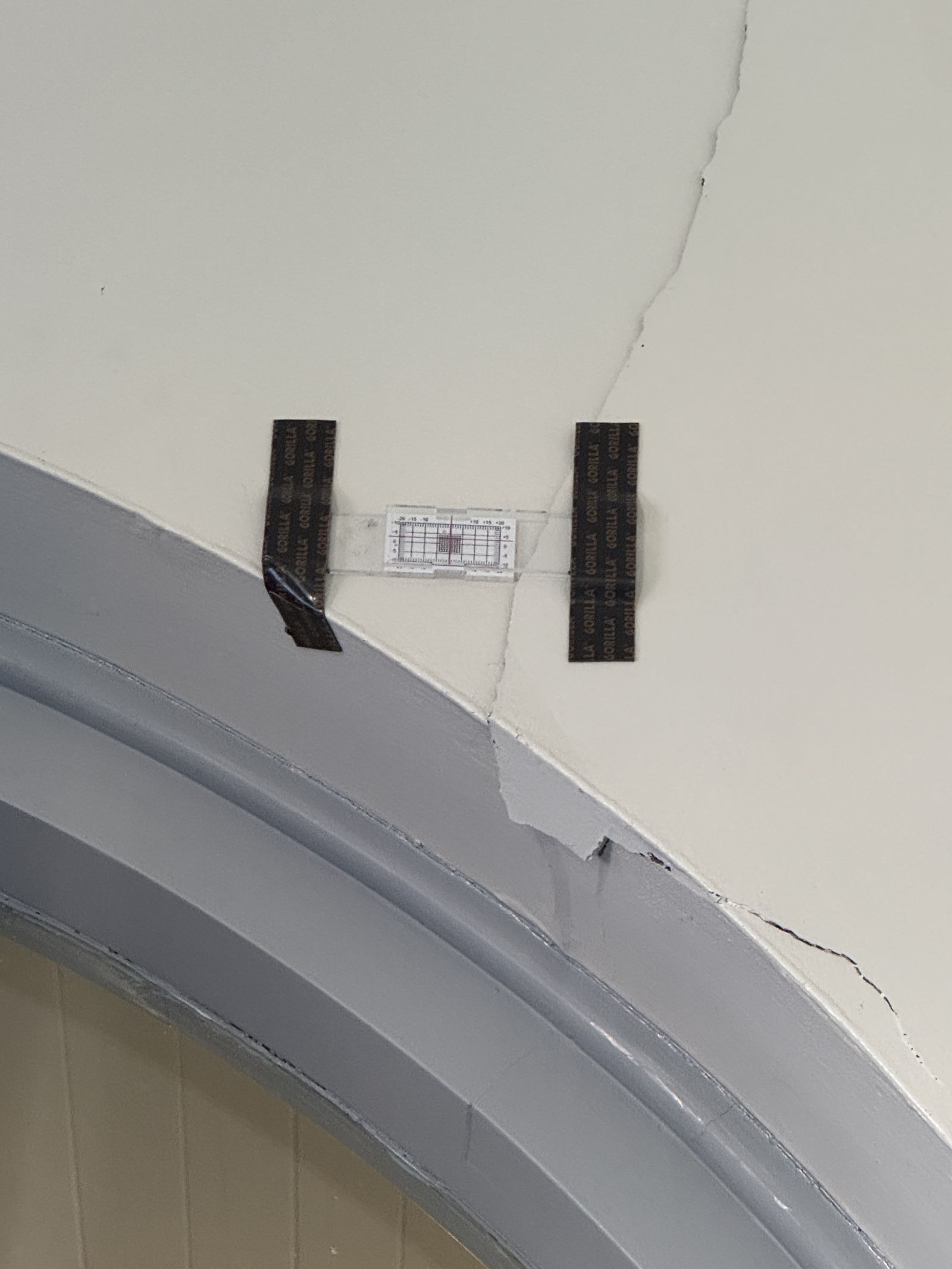 Crack monitoring gauge fixed across a crack in a wall beside an internal arch