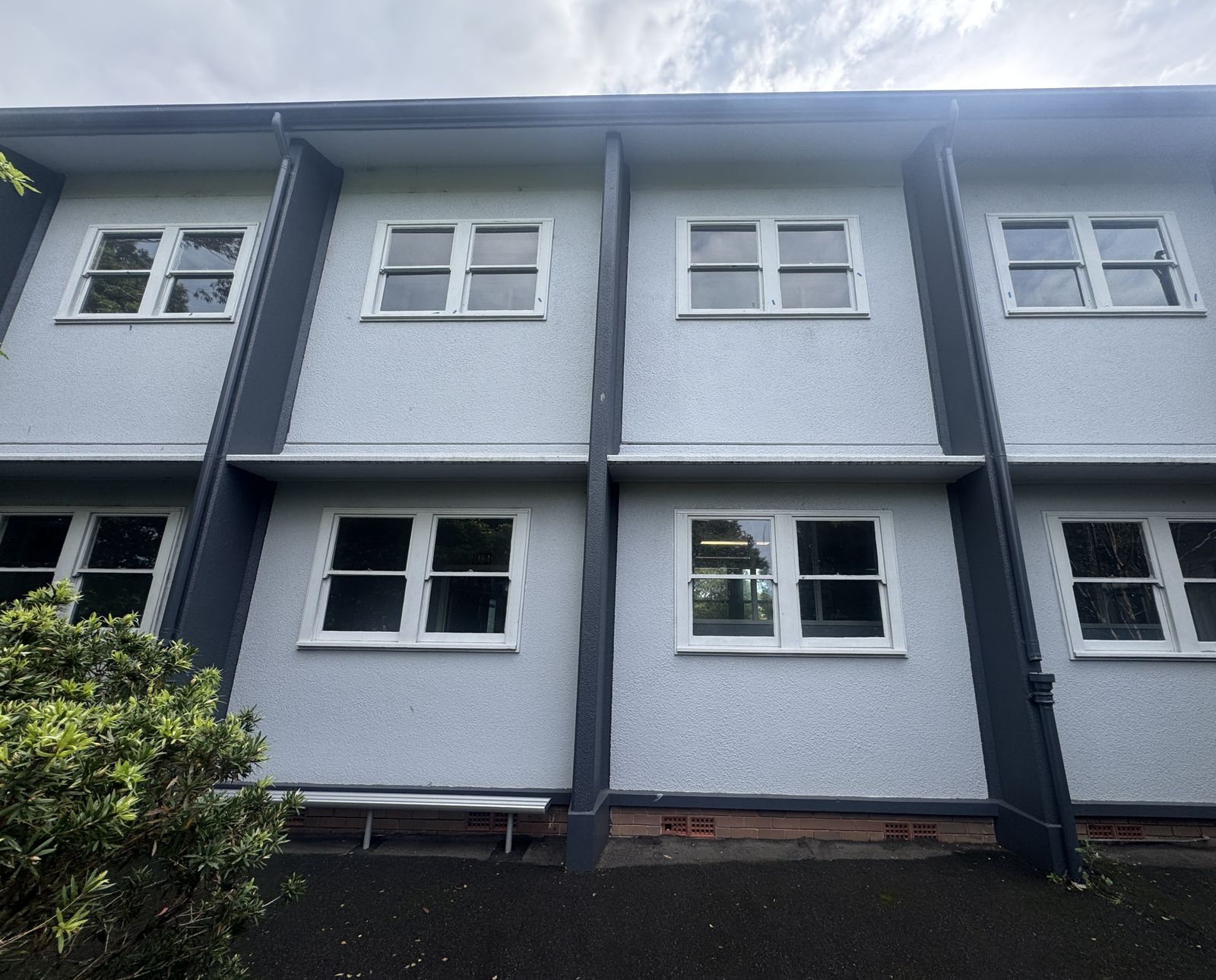 Freshly painted rendered facade with grey trims and white window frames on a two-storey building